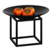 A black metal cube display stand with a bowl of persimmons on it.