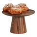 A Cal-Mil round walnut cake stand with pastries on it.