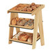 A Cal-Mil wooden 3-tier display rack holding bread and rolls on a table.