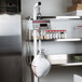 A Cardinal Detecto hanging scale on a metal shelf with a bag of food on it.