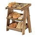 A Cal-Mil wood display rack with different types of bread on wood shelves.