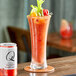 A glass of a red drink with a white can of Q Mixers Premium Bloody Mary Mix on a table.