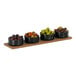 A Cal-Mil walnut rectangular serving board with bowls of green and black olives on a wood surface.