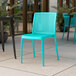 A blue Lancaster Table & Seating Rio resin side chair on an outdoor patio.