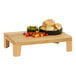 A wooden display stand with a bowl of bread and tomatoes on a table.