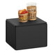 A black cube display stand with two baskets of fruit on top.