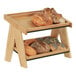 A wooden shelf with a 2-tiered display of bread on it.