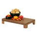 A Cal-Mil walnut display stand with a bowl of tomatoes on a wood table.