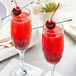 Two glasses of cherry cocktails with cherries on top.