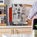 An Astra STA4800-RD gloss red automatic milk and beverage steamer with two wands on a countertop.