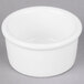 A white Tuxton ramekin on a gray surface.