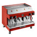 A red semi-automatic espresso machine with dual group heads and steam wands.