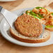 A Gardein veggie burger on a piece of bread with a plate of food and a knife.