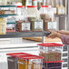 A woman reaching for a shelf with a Regency gray label holder to pour seeds into a container.