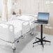 An Omnimed mobile adjustable laptop stand with a laptop on a hospital bed.