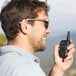 A man holding a Midland X-TALKER walkie talkie and smiling.