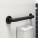 A Lavex 18" restroom grab bar with a matte black finish installed on a white wall.