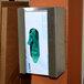 A stainless steel Omnimed disposable glove dispenser with a green glove in a box.