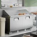 A stainless steel two-door mega top refrigerated sandwich prep table with a raised prep area and sandwiches on top.