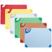 A white San Jamar cutting board with blue handles and several colorful boards.