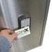 A person holding a card to a stainless steel cabinet with a keypad lock.