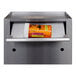 A stainless steel Omnimed medication drop box with a key lock and a bottle of pills inside.