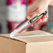 A hand using an Allway Tools Soft-Grip snap-off knife to cut a box.