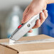 A hand using an Allway Tools Retractable Utility Knife to cut a box.