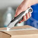 A hand holding an Allway Tools Soft-Grip Retractable Utility Knife cutting a box.