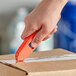 A hand using an Allway Tools Aluminum Safety Knife to cut a box.