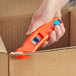 A hand holding an Allway Tools Pelican Dual-Function Safety Knife with 6 Blades box cutter.