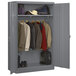 A dark gray metal Tennsco wardrobe cabinet with clothes and bags.