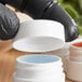 A person in black gloves holding a white container with red and blue gel.
