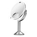 A simplehuman brushed stainless steel circular mirror on a stand with a light.