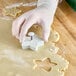 A person in gloves using an Ateco plastic star plunger cutter to cut out a cookie.