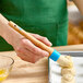 A person holding an Ateco round boar bristle pastry brush over food.