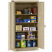 A Tennsco sand-colored metal storage cabinet with solid doors and many items on it.