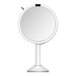 A round white stainless steel sensor mirror with a black stand.
