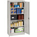 A Tennsco light gray metal storage cabinet with solid doors and many shelves filled with boxes.