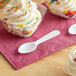 A bowl of ice cream with a Choice white plastic tasting spoon and sprinkles.