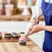 A person decorating cupcakes with an Ateco pastry bag.