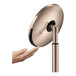A hand holding a simplehuman round rose gold sensor mirror.