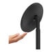 A hand reaching out to a round black simplehuman sensor mirror.