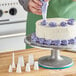 A person using an Ateco plastic piping tip to decorate a cake.