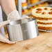 A person holding a Ateco stainless steel round cake mold over a cake.