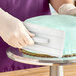 A hand using the white rectangular Ateco fondant smoother with a white handle to smooth fondant on a cake.