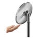 A close-up of a hand reaching out to touch a round metal surface.