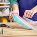 A person using an Ateco clear disposable pastry bag to pipe pink and blue frosting.