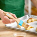 A person using an Ateco boar bristle baking brush to glaze pastries.