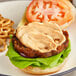 A burger with lettuce and a tomato slice on a plate.